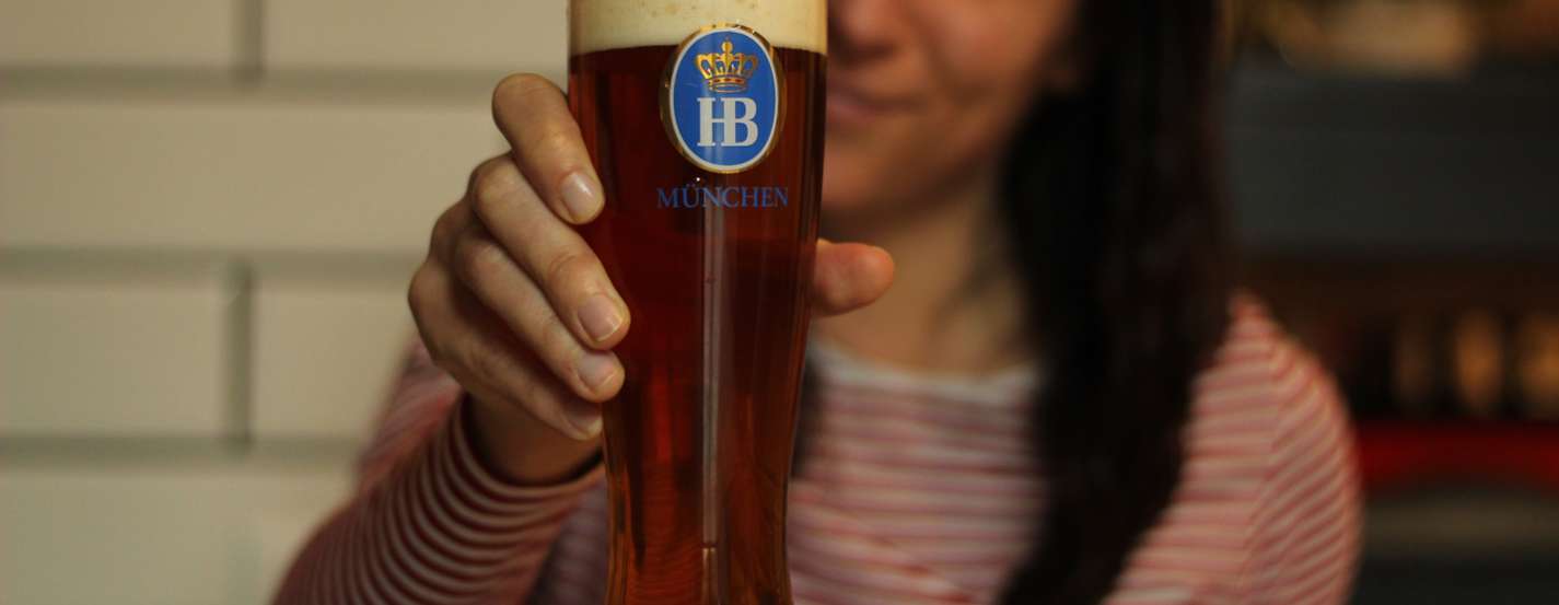 Frau hält Glas mit Münchner Bier